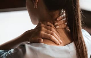 Mulher com mãos no pescoço representando doença profissional ou doença do trabalho.