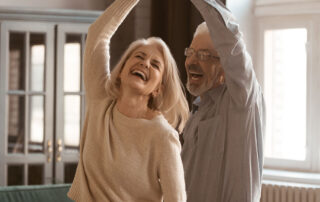 Casal de idosos dançando na sala de estar, simulação de felicidade devido a aprovação da revisão da vida toda.