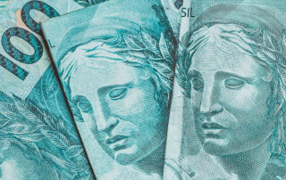 Fotografia colorida de notas de cem reais ilustram a capa da matéria: O governo vai antecipar o pagamento do décimo terceiro salário para aposentados e pensionistas do INSS e liberar saque de R$ 1 mil do FGTS.