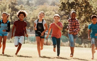 Ilustrando a capa da matéria “Lei Henry Borel: texto traz medidas protetivas para evitar novas agressões” exibimos uma fotografia colorida, de crianças correndo em um grande campo verde.