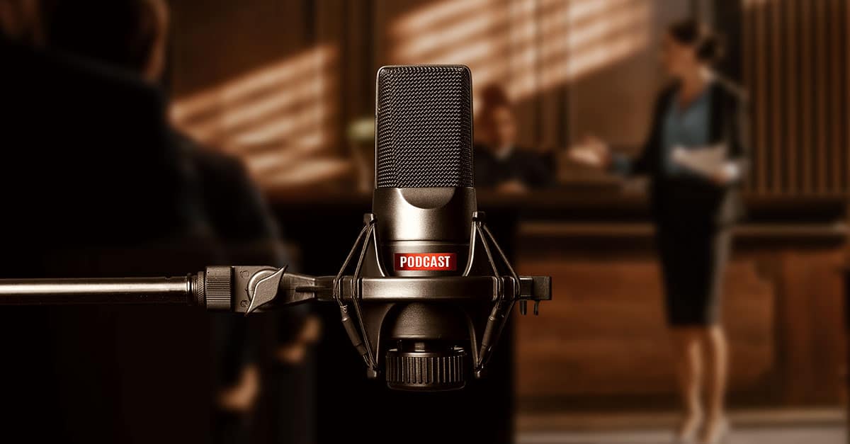 Fotografia colorida ilustra a capa da matéria "Podcasts para advogados e estudantes de direito: 5 boas opções". No primeiro plano vemos um microfone típico ao dispositivo utilizado pela maior parte dos podcasts. Em segundo plano é possível vislumbrar a sala de um tribunal.