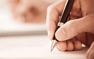 Ilustrando a matéria "Provas da OAB anteriores: Baixe os Exames de Ordem de 2019 até 2022" temos a fotografia de uma pessoa realizando um exame.