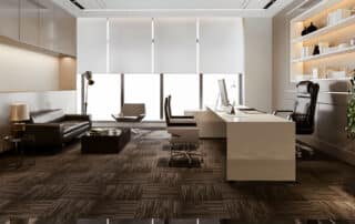 Como capa da matéria “Como fazer a decoração de escritórios de advocacia”, vemos um escritório de luxo com móveis em tons claros e paredes claras, uma mesa branca, sofá escuro, vaso com planta e prateleira com itens decorativos.
