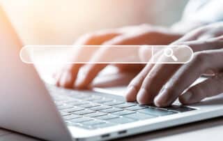 Como capa da matéria “O que seu site para advogados precisa ter”, vemos um homem usando um notebook, vemos apenas suas mãos e a imagem de uma barra de pesquisa.
