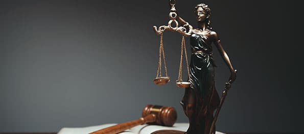 revisao-de-aposentadoria-aposentado-passou-a-receber-mais-que-o-dobro Para ilustrar a matéria “Revisão de aposentadoria: Aposentado passou a receber mais que o dobro”, sobre uma mesa vemos a estátua de uma mulher segurando uma balança, representando a Justiça, um martelo de juiz e um livro.