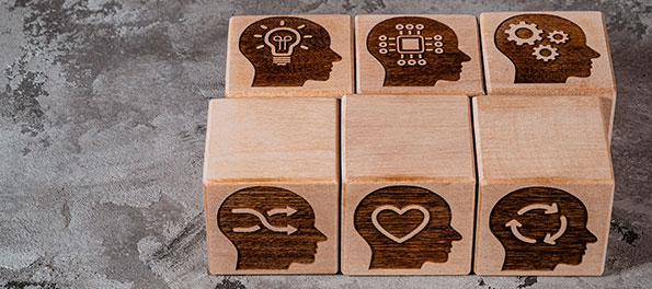 como-usar-gatilhos-mentais-na-advocacia Como ilustração da matéria “Como usar gatilhos mentais na advocacia”, vemos 6 blocos de madeira, cada um com a silhueta de um rosto e um símbolo no lugar do cérebro, como lâmpada, coração e engrenagens.