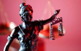 Como capa da matéria “Barbie e o Direito: Qual é a relação?”, vemos uma miniatura de uma estátua da justiça.