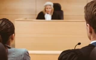 Como capa da matéria “Sustentação oral em diferentes áreas do Direito”, vemos dois advogados em um tribunal com uma juíza ao fundo.