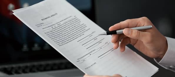 Alguém lendo um contrato e segurando uma caneta.