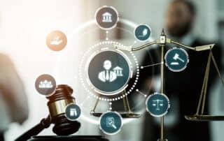 Como capa da matéria “Dicas para Ingressar no Mercado de Trabalho Jurídico”, vemos um martelo de juiz e uma balança da justiça sobre uma mesa com ícones do Direto flutuando na imagem.
