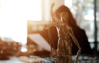 Como capa da matéria “Advocacia pública ou privada: qual escolher?”, vemos a imagem da Justiça em destaque com uma mesa de advogado desfocada ao fundo.